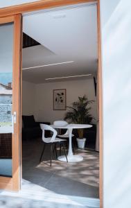 Eine Glastür öffnet sich zu einem Wohnzimmer mit einem Tisch und Stühlen. in der Unterkunft Apartma & RAfting in Kobarid