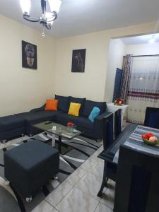 uma sala de estar com um sofá azul e uma mesa em Appartement Cosy & Chill em Douala