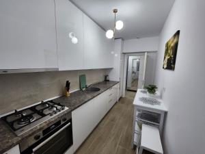 a kitchen with white cabinets and a sink and a stove at DeLux Apartments with Terassa in Towers Ever Green in Iaşi