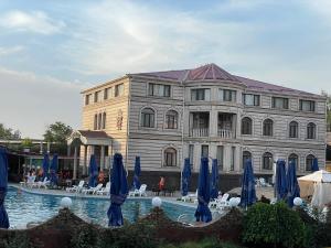 a building with blue umbrellas in front of a pool at Edem Hotel Shymkent in Shymkent