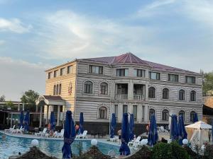 a building with blue umbrellas in front of a pool at Эдем in Shymkent