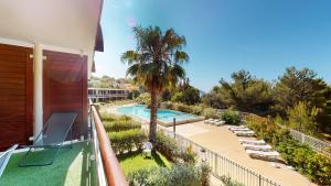 a balcony with a swimming pool and a palm tree at Les terrasses du Liouquet in La Ciotat