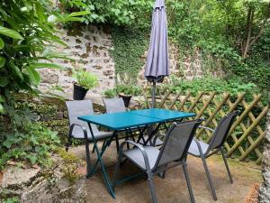 een blauwe tafel en stoelen met een paraplu bij L'Authentique maison de charme in Aubusson