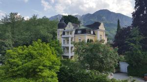 a large yellow house in the middle of trees at Apartmenthaus Salzburger Hof in Bad Reichenhall