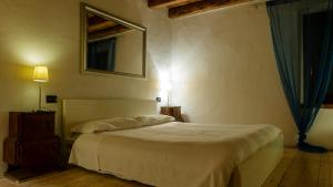 1 dormitorio con cama blanca y espejo en Agriturismo Trebisonda Country Resort, en Monzambano