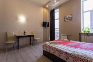 a bedroom with a bed and a table and a window at Malon Apartments in Kharkiv