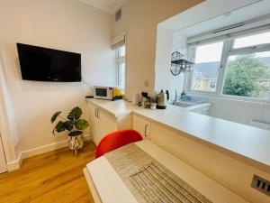 a kitchen with a white counter and a red chair at NEW modernised flat in the heart of Leigh on Sea in Southend-on-Sea