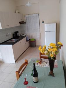 a kitchen with a table with a bottle of wine and flowers at Popi' s apartment 50 metres from the sea! in Sozopoli
