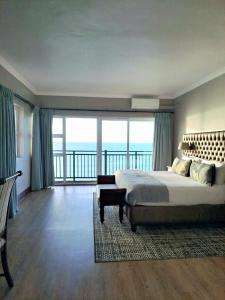 a bedroom with a large bed and a balcony at Diaz Hotel and Resort in Mossel Bay