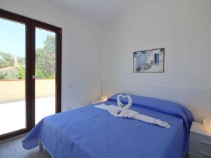 Un dormitorio con una cama azul con una cinta. en Apartment in Costa Rei en Monte Nai