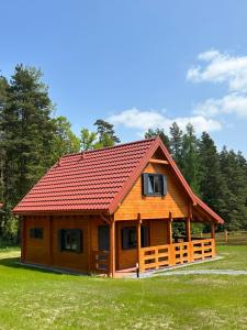 a large wooden cabin with a red roof at Okno na las in Polanica-Zdrój