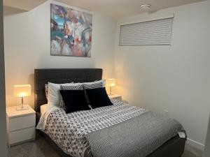 卡爾加里的住宿－Beautiful 2 bedroom home away from home，一间卧室配有一张带两盏灯和一幅画的床铺