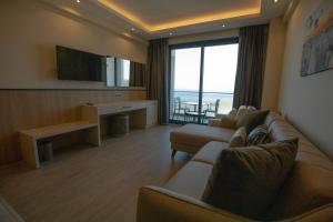 a living room with couches and a flat screen tv at Polaris Otel & Beach Club in Mersin