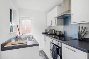 uma cozinha com armários brancos e um balcão preto em Fabulous and Stylish House in Nottingham em Mansfield