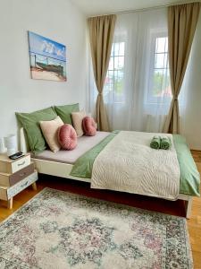 a bedroom with a bed with two green and pink pillows at Libás Apartman in Keszthely