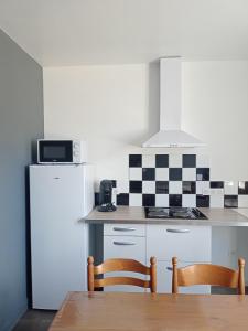 cocina con nevera, mesa y sillas en Appart 3 chambres, en Noyen-sur-Sarthe