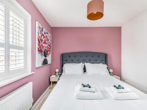 a bedroom with pink walls and a bed with two towels at Modern Comfortable Home Pass The Keys in Chichester