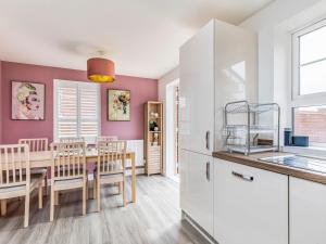 a kitchen and dining room with pink walls and a table at Modern Comfortable Home Pass The Keys in Chichester