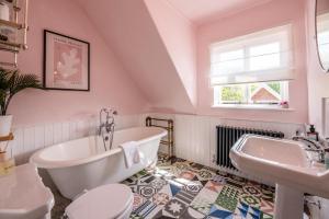 a bathroom with a tub and a toilet and a sink at Margo's Cottage, Orford in Orford