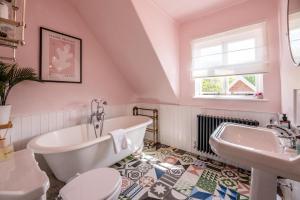 a bathroom with a tub and a toilet and a sink at Margo's Cottage in Orford