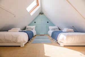 a attic bedroom with two beds and a window at Margo's Cottage in Orford