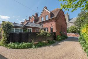 an old brick house with a fence in front of it at Margo's Cottage in Orford