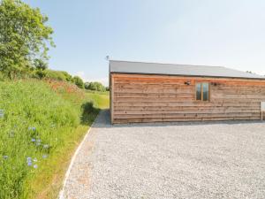 a wooden building with a gravel driveway next to a field at Watermead Lodge in Taunton