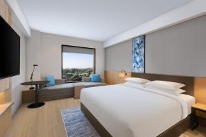 a bedroom with a large white bed and a living room at Fairfield by Marriott Dehradun in Dehradun