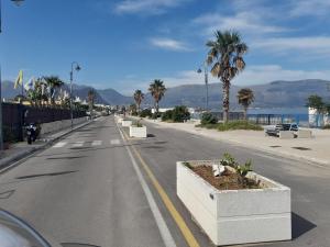 Une rue vide avec des palmiers et l'océan dans l'établissement Casa Vacanze Ciccinè, à Capaci