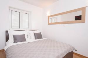 ボルにあるVilla Dalmatia Apartmentsのベッドと鏡のある白い寝室