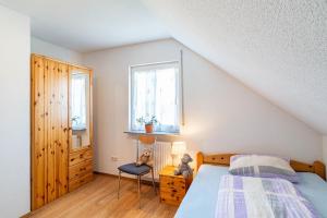 a bedroom with a bed and a chair and two windows at Schwalbenhof Dreßler und Duss für 6 in Bad Herrenalb