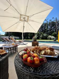 - un panier de fruits et de pain sur une table avec un parasol dans l'établissement Villa Pauline, à Avignon
