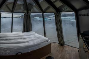 a bed in a tent with a view of the water at Fjallsarlon - Overnight adventure in Hnappavellir