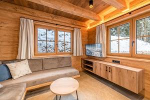 a living room with a couch and a tv at Poolchalet Dachsteinblick in Pruggern