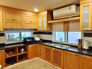 a kitchen with wooden cabinets and a sink and windows at 芭提雅市中心4间卧室泳池别墅好莱坞Hollywood旁-19 in Pattaya Central