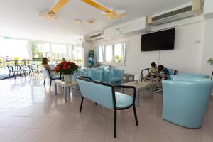 comedor con sillas azules y TV de pantalla plana en Hotel Croce Del Sud, en Rímini