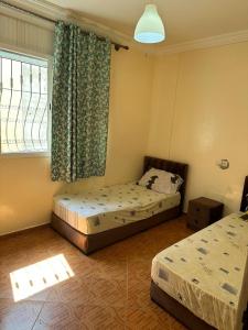 a bedroom with two beds and a window with curtains at Hay mohammadi agadir in Agadir