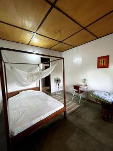 ein Schlafzimmer mit einem Himmelbett und einem Schreibtisch in der Unterkunft Villa calme - Jardin Tropical - Kpalimé in Palimé