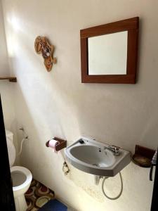 baño con lavabo y espejo en la pared en Villa calme - Jardin Tropical - Kpalimé, en Palimé