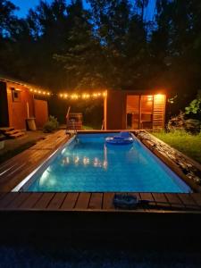 a swimming pool in a backyard at night with lights at Dziki zakątek Piskornia dom z sauną in Piskornia