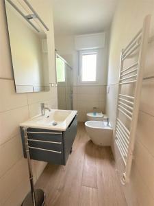 bagno con lavandino, servizi igienici e specchio di Villaggio Azzurro Plus a Bibione