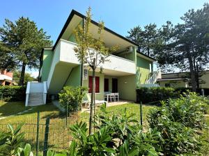 une maison verte et blanche avec une clôture dans l'établissement Villaggio Azzurro Plus, à Bibione
