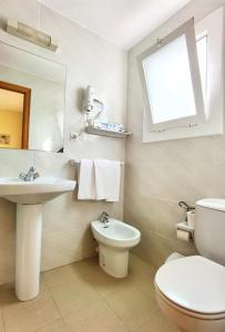 a bathroom with a sink and a toilet and a mirror at Hostal Noray in Sant Feliu de Guíxols