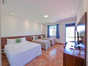 a hotel room with two beds and a television at Pousada Ouro Preto de Bonito in Bonito