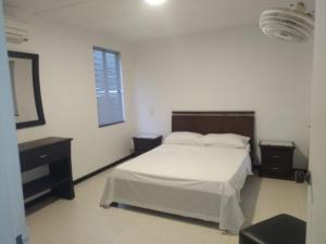 a white bedroom with a bed and a mirror at Apartamento San José in Melgar