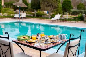 uma mesa com comida e bebidas junto a uma piscina em RIAD LES DEUX MONDES em Essaouira