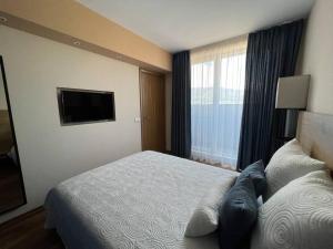 a hotel room with a bed and a flat screen tv at Cozy and bright apartment in Sofia