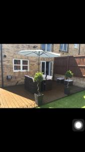 a patio with an umbrella and two chairs and a table at Entire 3 bedroom deluxe house in Cleckheaton