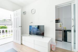 a white kitchen with a flat screen tv on a white cabinet at White House Apartment - Chalong in Chalong 