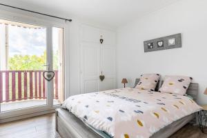 a white bedroom with a bed and a balcony at Cocooning in Mont-de-Marsan